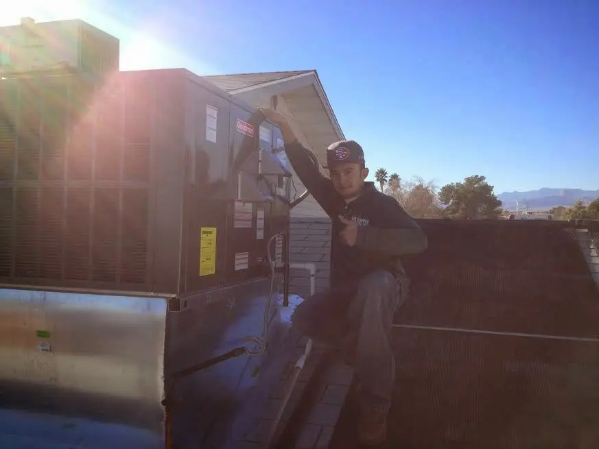 HVAC technician performing AC Tune-Up on a rooftop unit in Fruit Heights