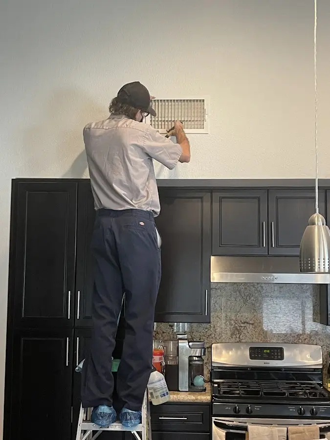 Technician inspecting an air vent during HVAC service in Fruit Heights